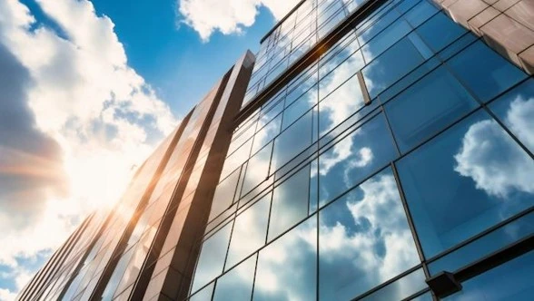 Façade vitrée de bâtiment contemporain reflétant le ciel en contre-plongée